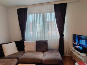 a living room with a couch and a window at Cozy near City Center Apartment! in Pristina