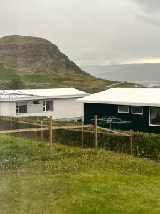 a white and black house with a hill in the background at Sigtún 4 in Patreksfjörður