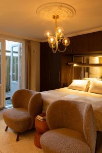 een slaapkamer met een groot bed en 2 stoelen bij B&B Midtown Amsterdam suites in Amsterdam