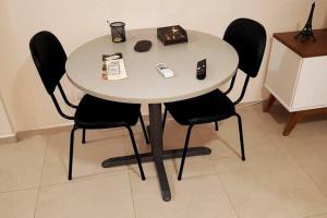 a white table with four black chairs in a room at Studio 1811 Campinas SP in Campinas