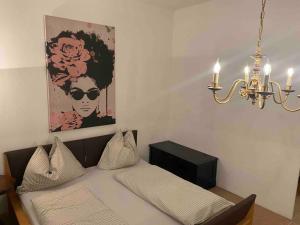 a bedroom with a bed with a chandelier and a picture at Seenahes Haus mit Hot Tub in Krumpendorf am Wörthersee