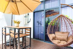 a hanging hammock chair next to a table and an umbrella at Homesuite' Home at The Shore in Kota Kinabalu
