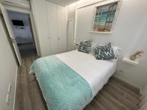 a small white bedroom with a bed and a window at Ascensor à Vista in Nazaré