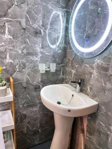 a bathroom with a white sink and a stone wall at Roswell Luxury Properties Yaoundé - Quartier FOUDA in Yaoundé