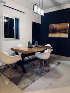 une salle à manger avec une table en bois et des chaises blanches dans l'établissement Roswell Luxury Properties Yaoundé - Quartier FOUDA, à Yaoundé