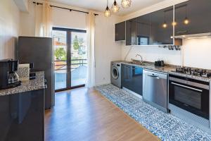 a kitchen with stainless steel appliances and wooden floors at Modern 3 bedrooms 3 bath apartment 5 minutes walk from the Santuary in Fátima