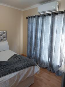 a bedroom with a bed and blue curtains at Home Life Guesthouse in Midrand