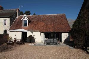 a white building with chairs and tables in front of it at La Pidellerie bord de Cher-Châteaux de la Loire in Véretz