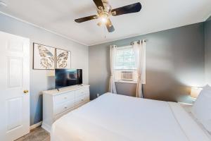 1 dormitorio con cama blanca y ventilador de techo en Neverending Beauty en Glens Falls