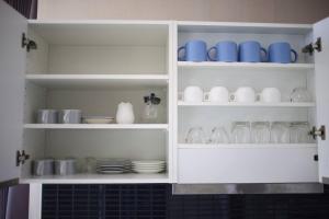 a white cabinet filled with dishes and glass jars at Stunning Spacious Mountain View Apartment in Chiang Mai