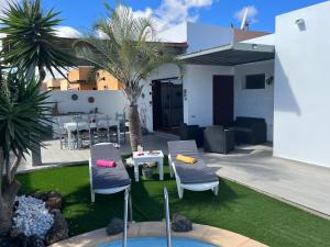 eine Terrasse mit 2 Stühlen, einem Tisch und Palmen in der Unterkunft Villa Papi in La Oliva