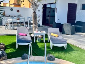 zwei Stühle und ein Tisch in einem Hof mit einem Tisch und einem Tisch in der Unterkunft Villa Papi in La Oliva