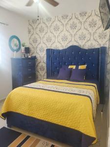 uma cama azul com um cobertor amarelo e almofadas roxas em Hermoso Apto. en Bani, Rep. Dom. em Baní