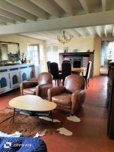 sala de estar con sillas de cuero y mesa en Maison entière avec piscine chauffée 4p, en Brétigny