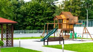 un parque infantil con una casa en el árbol y un tobogán en Trevilles Apartamenty - Stone Hill z basenem i SPA, en Szklarska Poręba