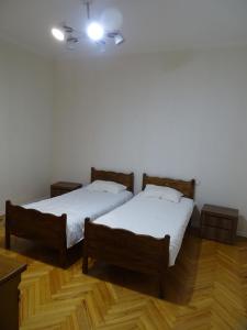 two beds in a room with wooden floors at Vake Super Quiet and Comfy Apartment with a Yard in Tbilisi City