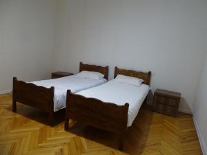 two beds in a room with wooden floors at Vake Super Quiet and Comfy Apartment with a Yard in Tbilisi City