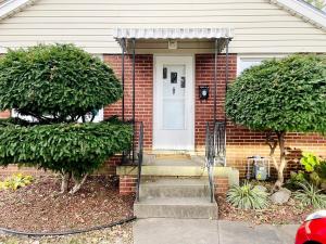 a brick house with a white door and two trees at Central Chic on Washington in Evansville