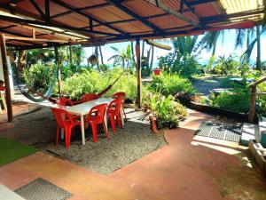 een patio met een tafel en stoelen en een schommel bij Tortuguero Adventures Beach House in Tortuguero