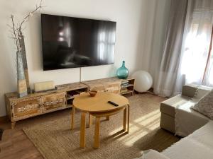 ein Wohnzimmer mit einem Tisch und einem großen TV in der Unterkunft Apartamento céntrico, climatizado y totalmente equipado de 3 habitaciones para 6-7 personas in Santa Coloma de Farners
