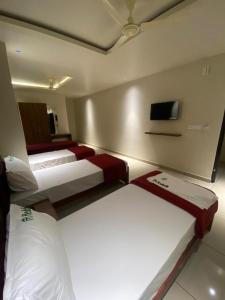 a room with three beds and a tv on the wall at Redbell Suites Kizhisseri in Kondotti