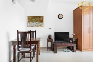 Habitación con escritorio, TV, mesa y sillas. en Phineek Homes Elegant Studio Lake Side IMPZ Production City, en Dubái