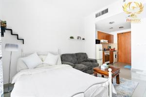 1 dormitorio con 1 cama y sala de estar en Phineek Homes Elegant Studio Lake Side IMPZ Production City, en Dubái