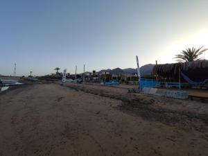 a dirt road with a building and palm trees at White palace camp (ex camp David) in Nuweiba