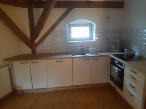 a kitchen with white cabinets and a sink and a window at Staré děkanství in Úterý