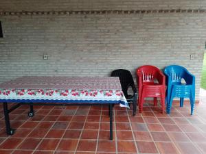 vier stoelen en een tafel voor een stenen muur bij Mi Refugio La Herencia in Caacupé
