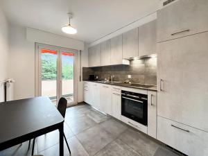 a kitchen with white cabinets and a table and a window at Castelview - Sion next to the old town in Sion