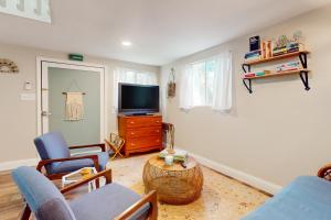 sala de estar con TV, sillas y mesa en Bunglow Boogie Bunkhouse, en New Port Richey