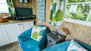 una stanza con un divano blu in una casetta di Ynys Hideout a Moelfre