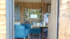 eine Küche mit blauen Stühlen, einem Tisch und einem Fenster in der Unterkunft Ynys Hideout in Moelfre