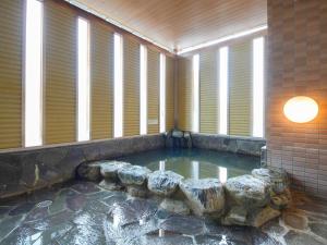 una piscina de agua en una habitación con ventanas en APA Hotel Takasaki Ekimae, en Takasaki