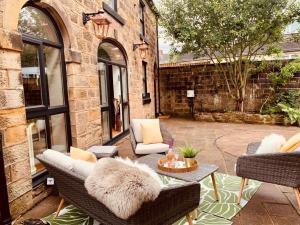 a patio with two chairs and a table with a couch at Luxury Family Coach House,Riber Castle Views,Easy Walk into Matlock Centre in Matlock