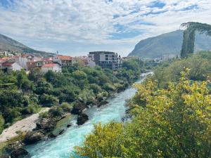 Blick auf einen Fluss mit Gebäuden und eine Stadt in der Unterkunft Boutique Apartment Mostar in Mostar