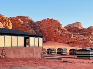 a building in the desert with mountains in the background at Bedouin Nights Camp in Wadi Rum