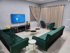 sala de estar con muebles verdes y TV de pantalla plana en Dolly House, en Tema