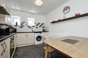 a kitchen with a table and a washing machine at 3- Bedroom modern,spacious apartment-Devon in Newton Abbot