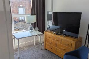 a living room with a tv and a table with a lamp at 3- Bedroom modern,spacious apartment-Devon in Newton Abbot