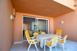 a dining room with a white table and yellow chairs at Puig sa Guilla 1C B3 in Pals