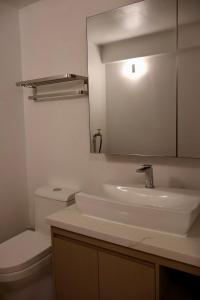 W łazience znajduje się umywalka, toaleta i lustro. w obiekcie Blue Whale Villa - Deluxe Suite w mieście Calibishie