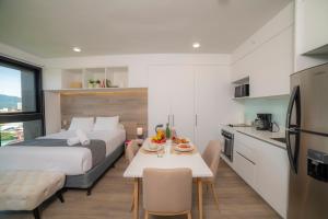 a bedroom with a bed and a table and a kitchen at BEE Suites Escalante in San José