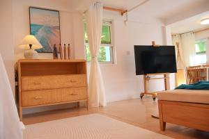 a bedroom with a dresser and a flat screen tv at Blue Whale Villa - Deluxe Suite in Calibishie