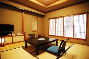 ein Wohnzimmer mit einem Tisch und einem TV in der Unterkunft Ibusuki Syusui-en in Ibusuki