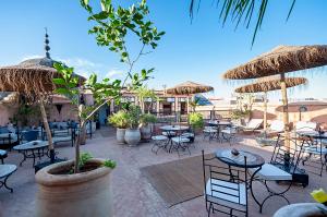 a patio with tables and chairs and umbrellas at Riad Dar Nadwa in Marrakesh