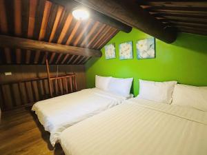 2 camas en una habitación con una pared verde en 時光旅舍古厝一館, en Jinning