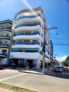 a building on a street with a person walking in front of it at Apto frente mar 3 suites Castelhanos ES in Anchieta