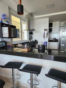 a kitchen with a counter and two bar stools at Apto frente mar 3 suites Castelhanos ES in Anchieta
